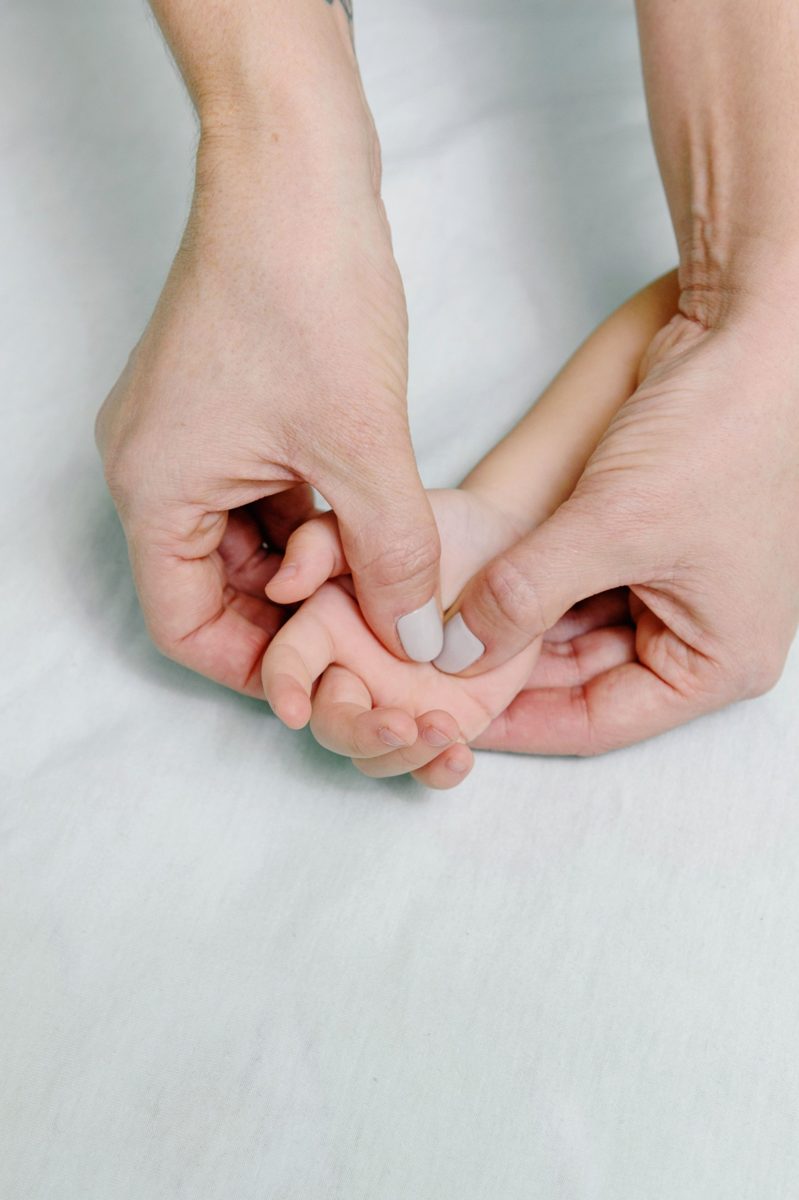 A parent gently massaging a baby's hand